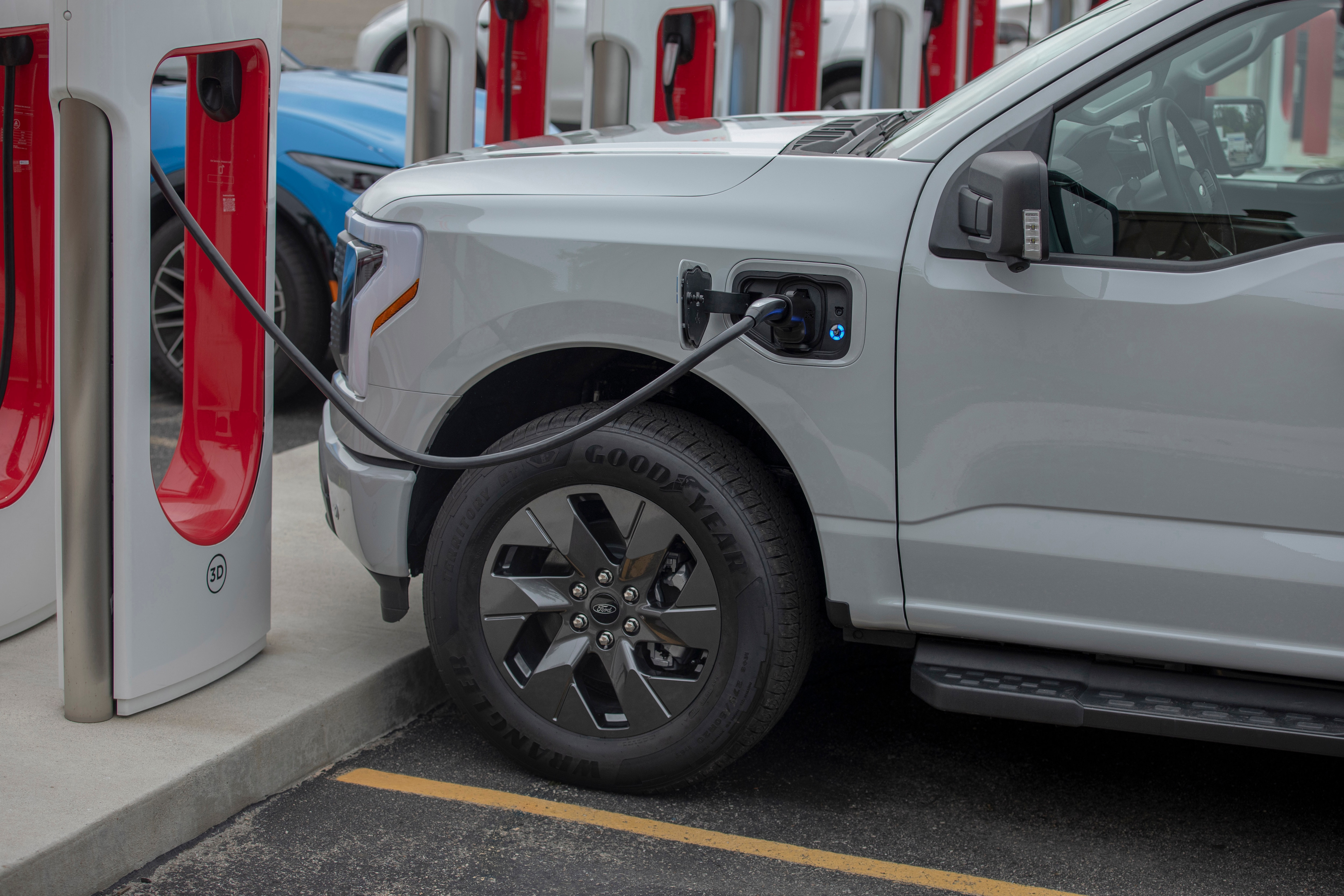 A man plugs a charger into his electric vehicle.